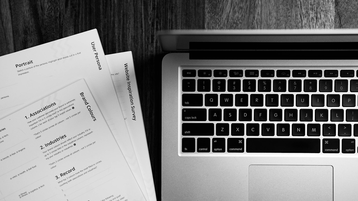 Laptop and business documents on a wooden desk.