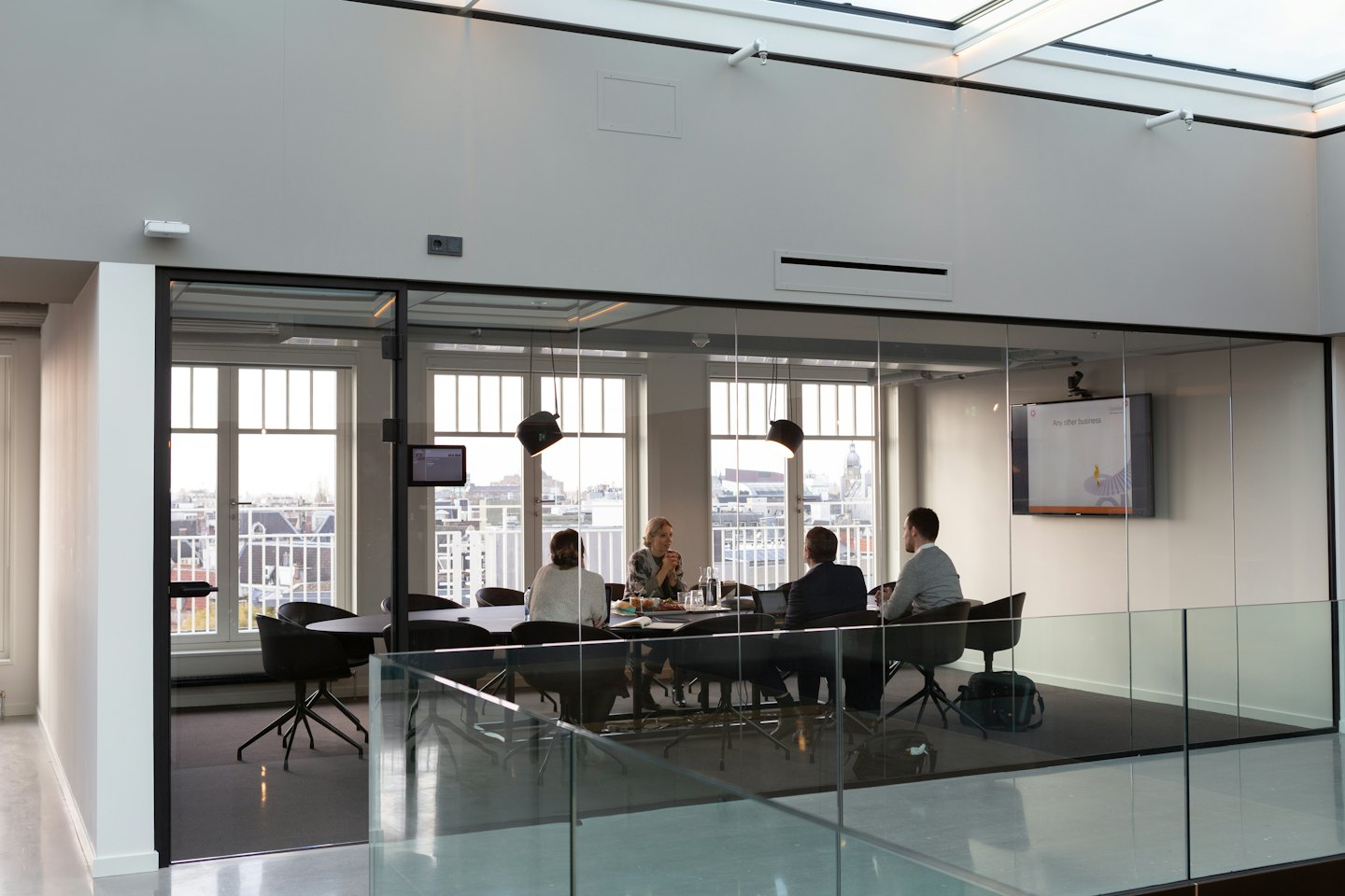 Four professionals collaborate around a conference table with monitors.