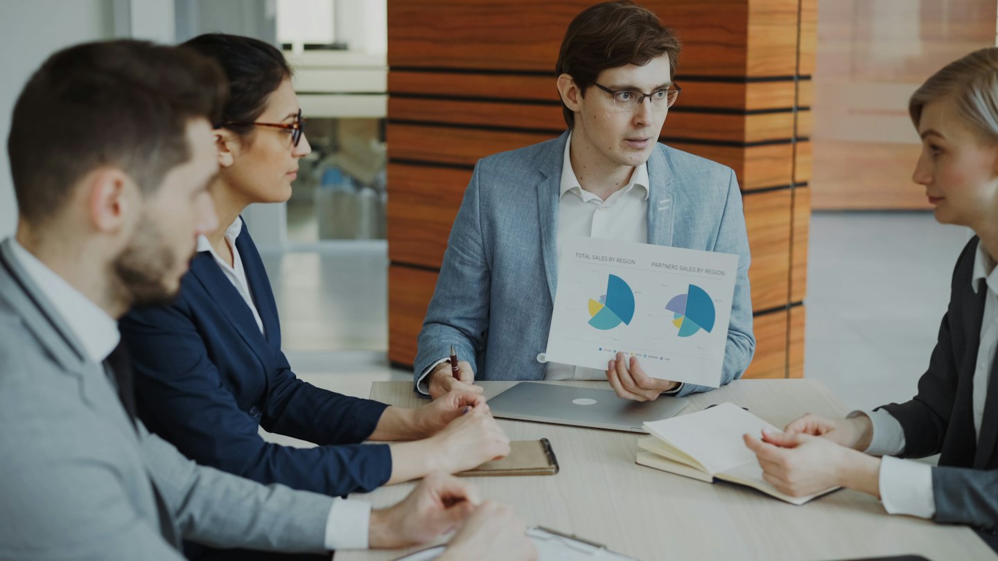 Business people meeting and discussing colorful charts at a conference table.